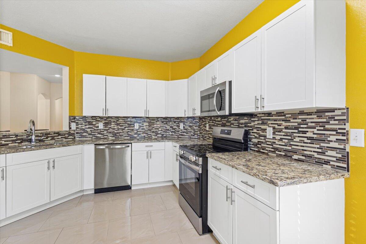 110 Southwest Peacock Boulevard, Unit 6101 Port St. Lucie, FL 34986 - Photo 24 of 70 a kitchen with stainless steel appliances granite countertop a sink and a stove