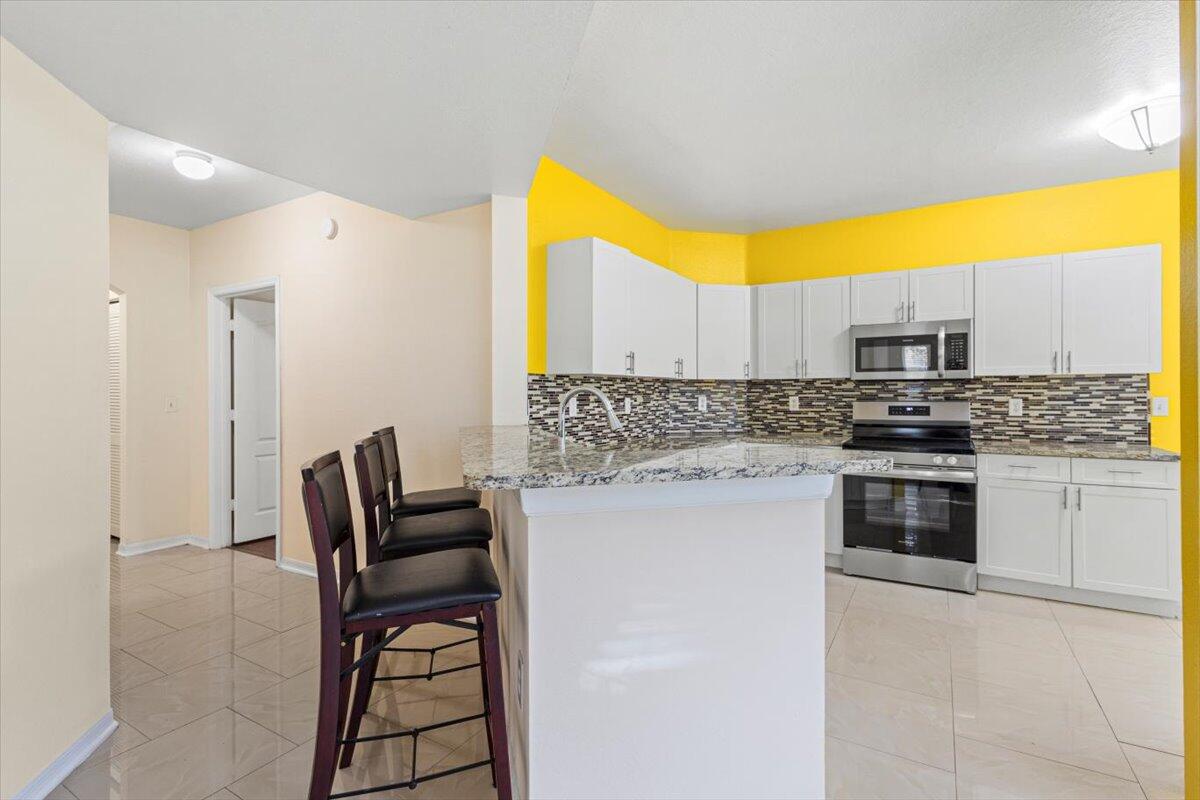 110 Southwest Peacock Boulevard, Unit 6101 Port St. Lucie, FL 34986 - Photo 26 of 70 a kitchen with a stove a sink and a microwave