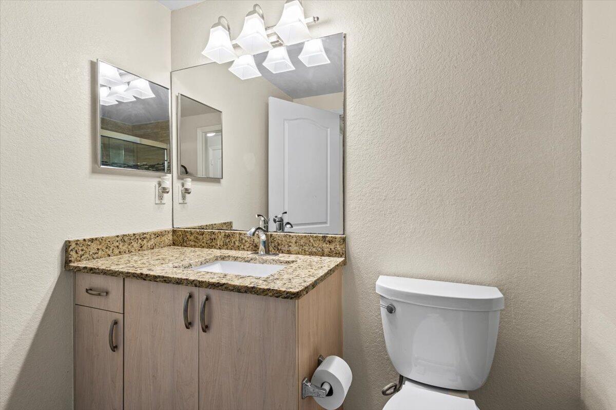 110 Southwest Peacock Boulevard, Unit 6101 Port St. Lucie, FL 34986 - Photo 43 of 70 a bathroom with a granite countertop sink a toilet and mirror