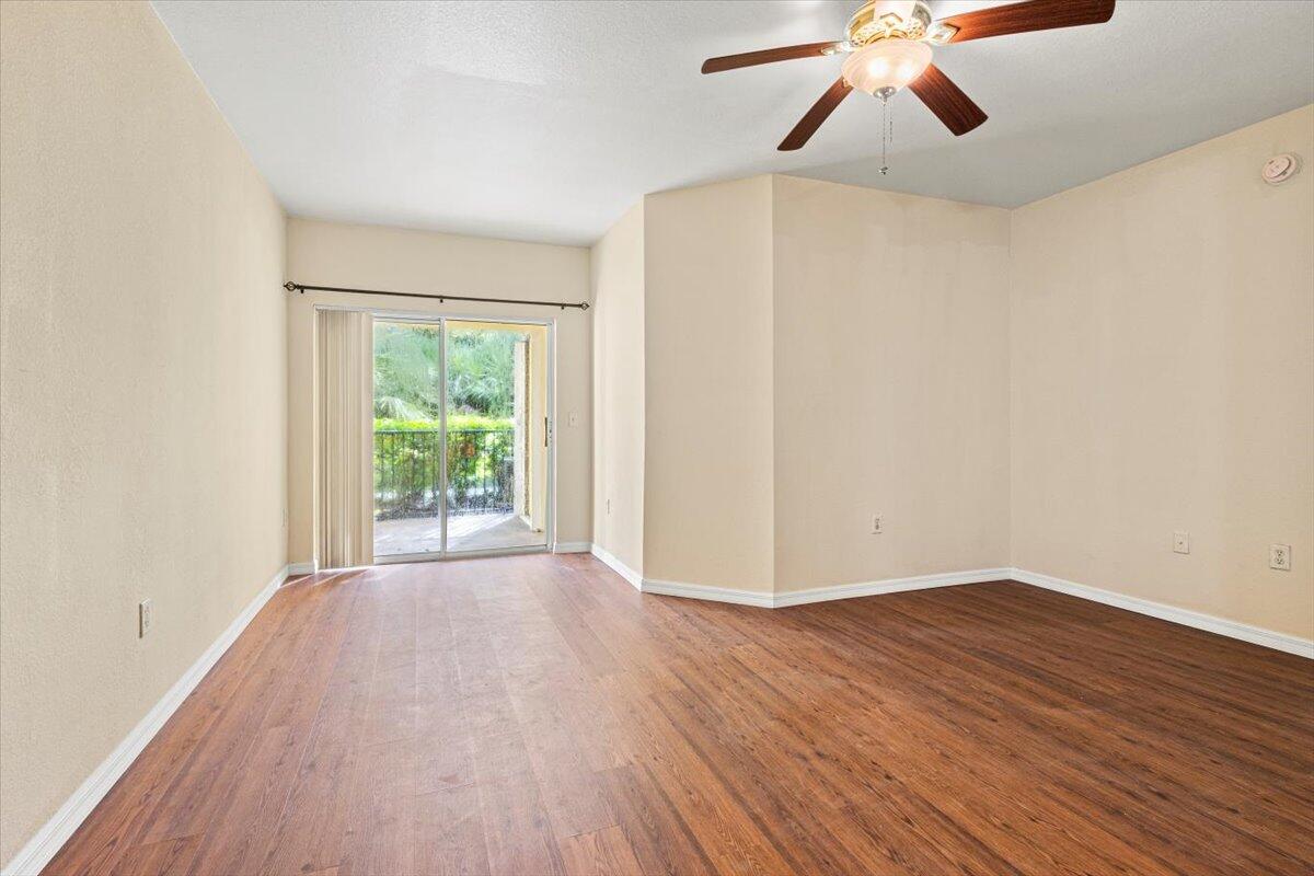 110 Southwest Peacock Boulevard, Unit 6101 Port St. Lucie, FL 34986 - Photo 8 of 70 an empty room with wooden floor chandelier fan and windows