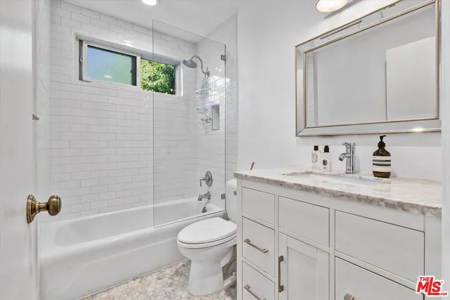 a bathroom with a granite countertop sink a toilet and bathtub