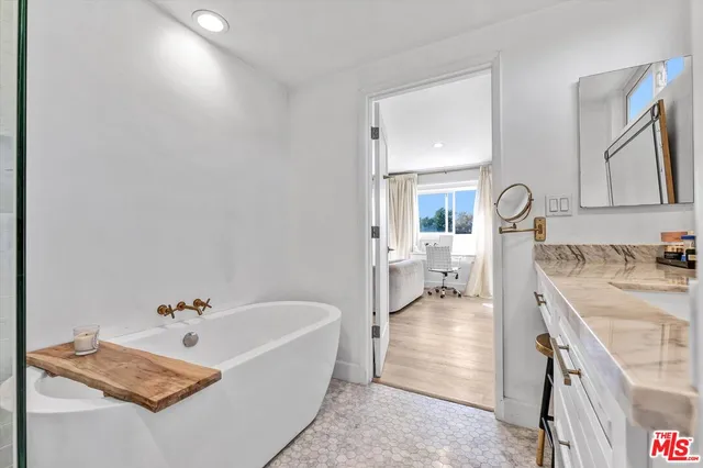 a bathroom with a tub double vanity and a sink