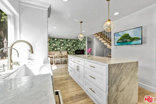 a large kitchen with kitchen island a large counter top space a sink stainless steel appliances and cabinets