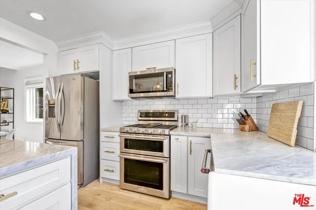 a kitchen with stainless steel appliances granite countertop a stove a refrigerator and a microwave