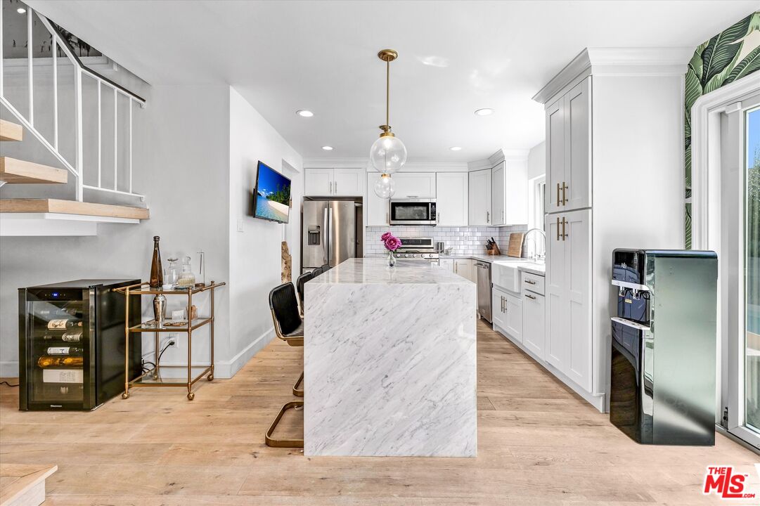 5101 Keli Court Los Angeles, CA 90066 - Photo 10 of 29 a kitchen with stainless steel appliances kitchen island granite countertop a refrigerator oven a sink dishwasher and white cabinets with wooden floor