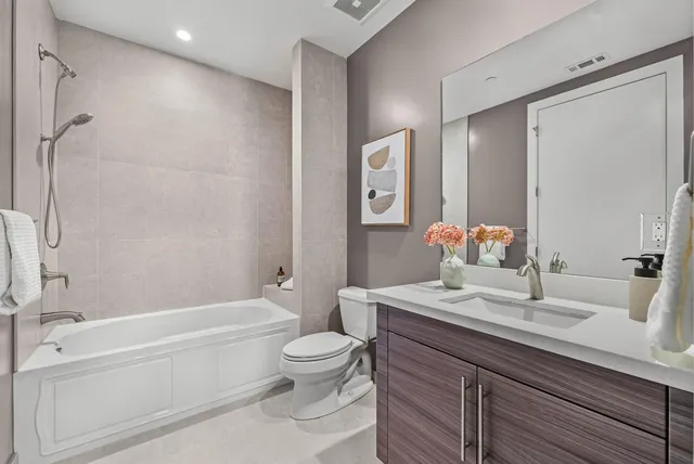 a bathroom with a granite countertop bathtub shower sink mirror vanity and toilet