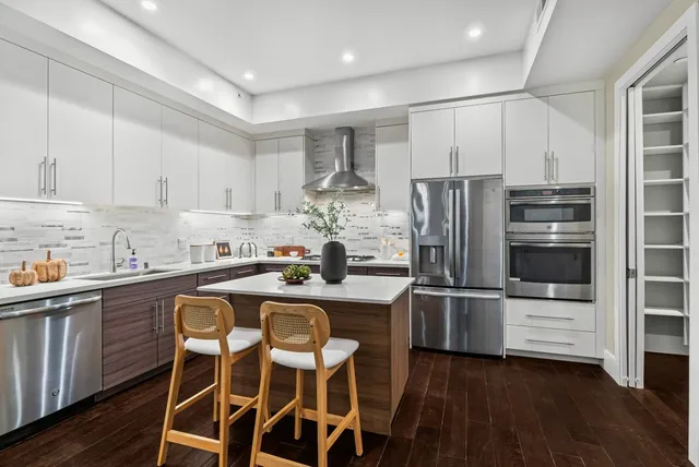 a kitchen with kitchen island white cabinets and stainless steel appliances