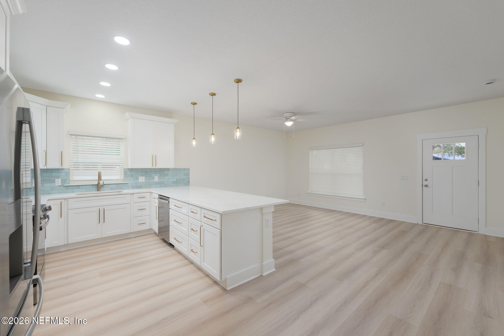 688 Madeore Street St. Augustine, FL 32084 - Photo 7 of 28 a large kitchen with a refrigerator a sink dishwasher a stove and white cabinets with wooden floor