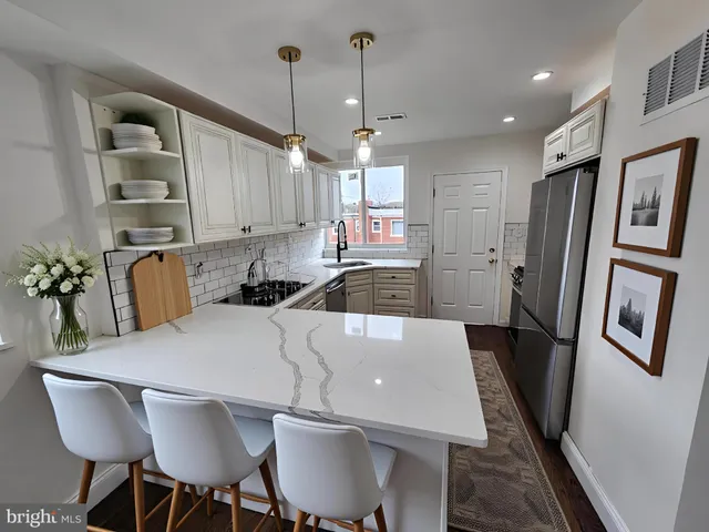 a kitchen with stainless steel appliances granite countertop a refrigerator a sink a stove a dining table and chairs