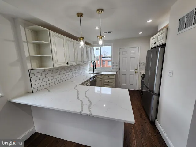 a kitchen with stainless steel appliances a refrigerator a sink a stove and white cabinets