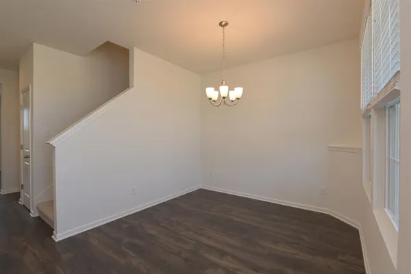 a view of an empty room with wooden floor and a chandelier