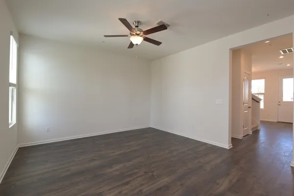 an empty room with wooden floor and a ceiling fan