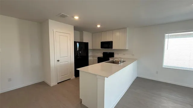 a kitchen with a refrigerator a microwave a sink and cabinets