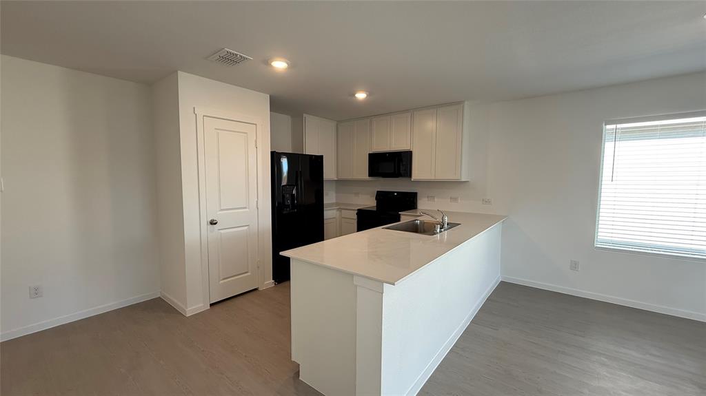 6725 Haines Drive Princeton, TX 75407 - Photo 5 of 25 a kitchen with a refrigerator a microwave a sink and cabinets