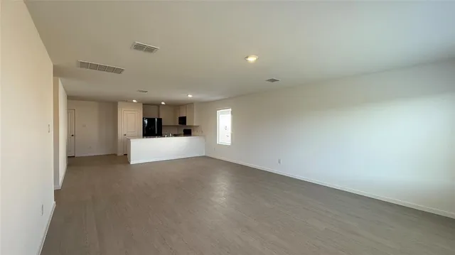 a view of a big room with wooden floor and windows