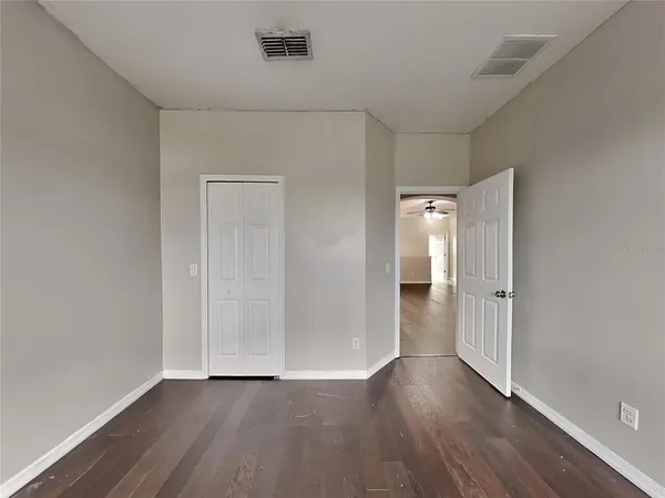 a view of an empty room with wooden floor and closet
