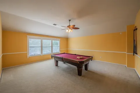 an empty room with chandelier fan and windows