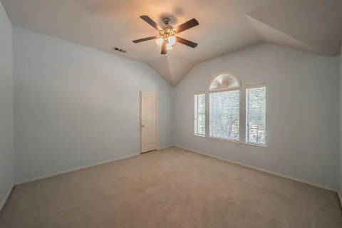 an empty room with chandelier fan and windows
