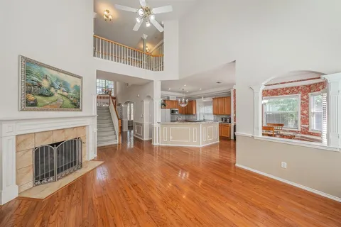 a view of a livingroom with furniture wooden floor a fireplace and windows