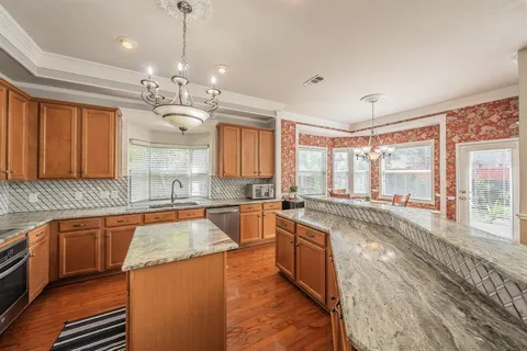 a large kitchen with stainless steel appliances granite countertop a lot of counter space and a sink