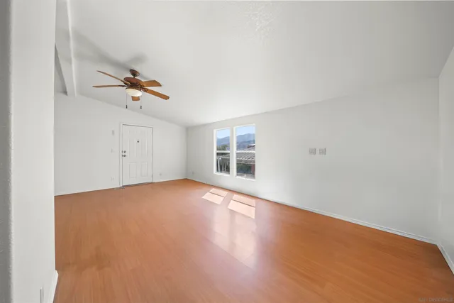 an empty room with a wooden floor and windows