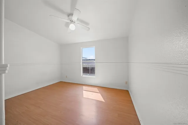 an empty room with a window and a fan