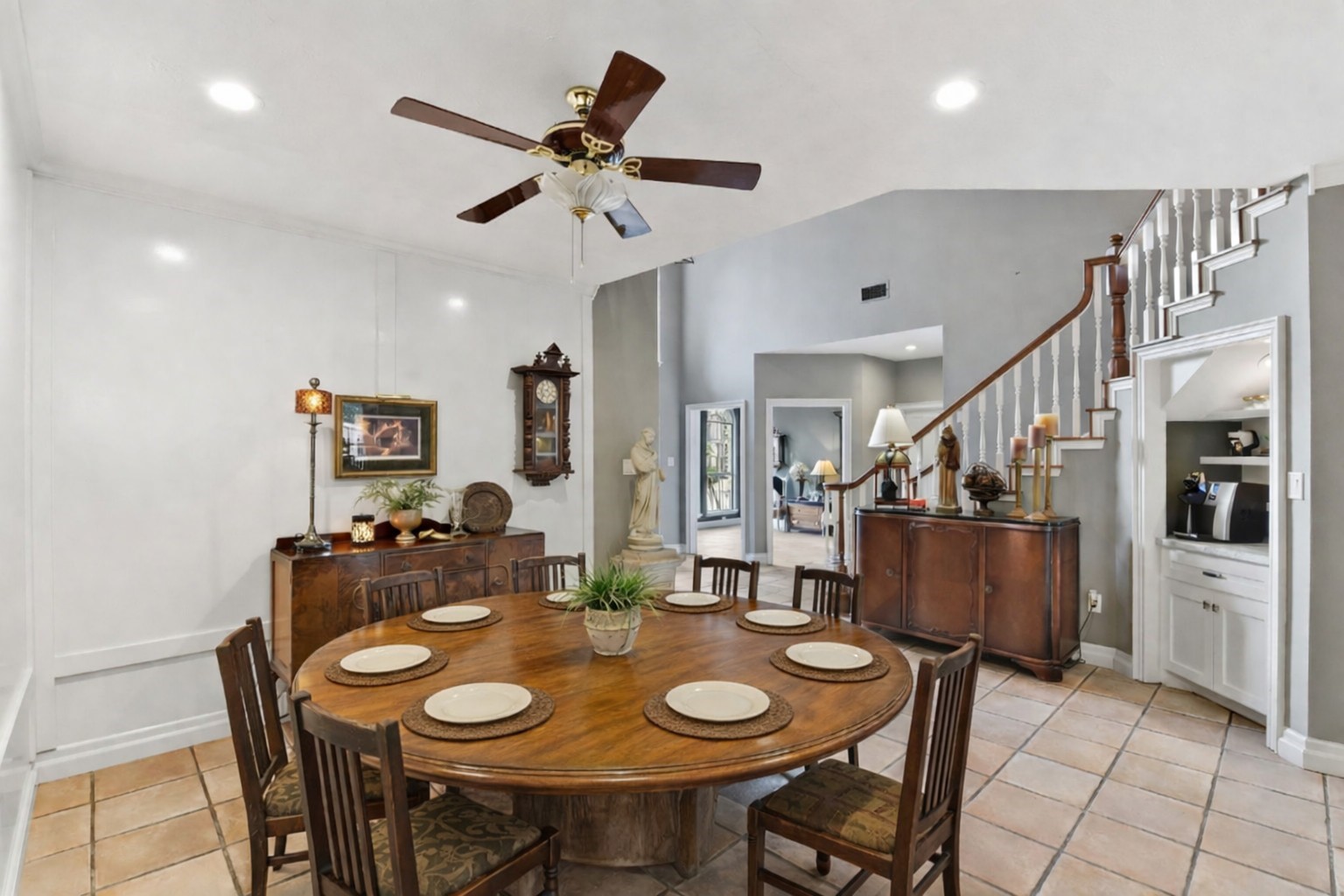 16322 Cranwood Drive Spring, TX 77379 - Photo 12 of 42 Experience elegant dining in this inviting space, featuring a charming wooden table set under a classic ceiling fan, with a graceful staircase and cozy living area just beyond.