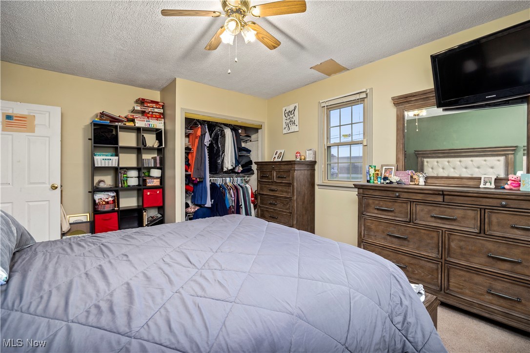 5569 Lear Nagle Road North Ridgeville, OH 44039 - Photo 22 of 41 Owners bedrrom, Bedroom with ceiling fan, a textured ceiling, light carpet, and a closet