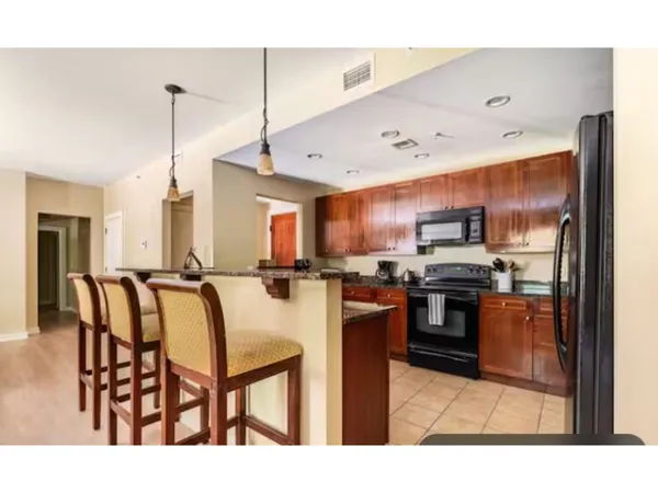 a kitchen with stainless steel appliances kitchen island granite countertop a refrigerator a stove a sink a dining table and chairs with wooden floor