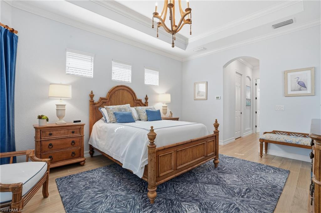 9923 Corso Bello Drive Naples, FL 34113 - Photo 24 of 47 a bedroom with a bed and a chandelier
