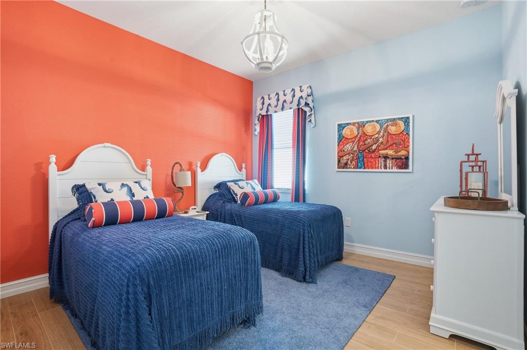 9923 Corso Bello Drive Naples, FL 34113 - Photo 27 of 47 a bedroom with two beds and a chandelier