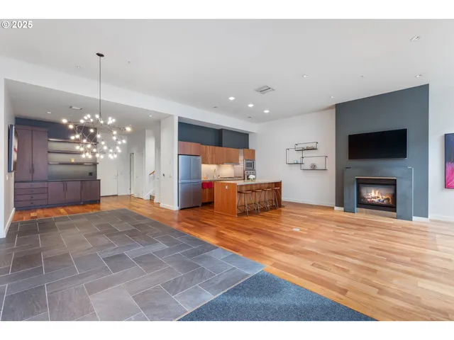 a view of a livingroom with a fireplace a chandelier and wooden floor