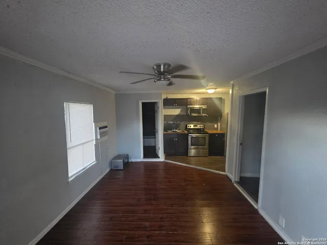 a view of a hallway with wooden floor and a kitchen