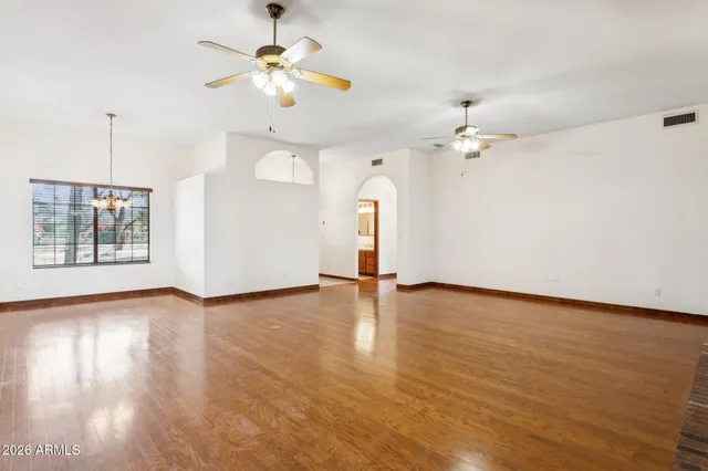 a view of an empty room with a window and wooden floor