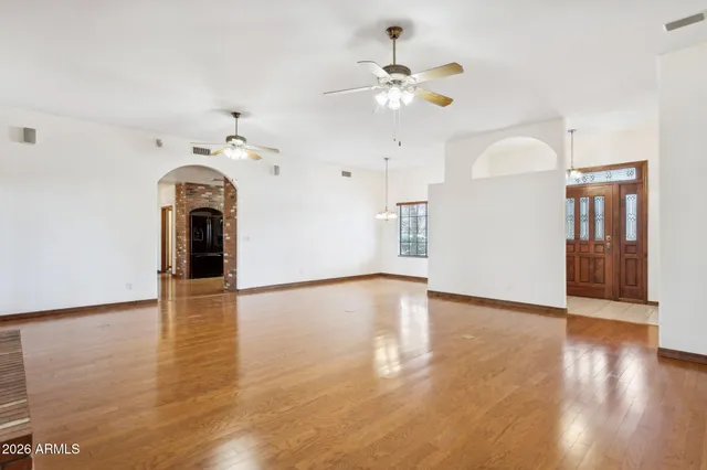 a view of an empty room with wooden floor and a kitchen