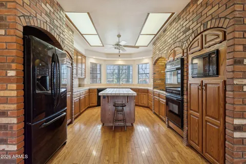 a kitchen with stainless steel appliances granite countertop a refrigerator a stove and a wooden floors