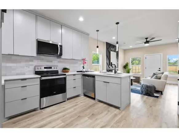 a kitchen with a sink stove cabinets and wooden floor