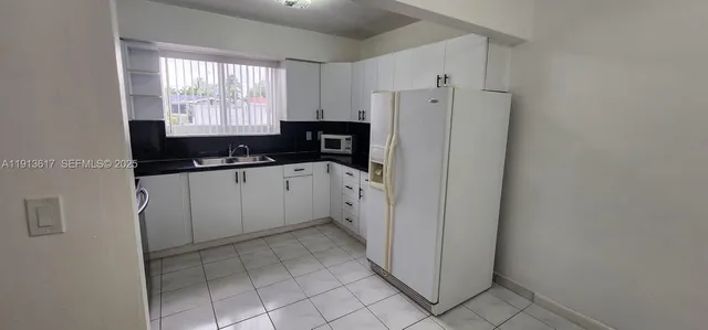 a kitchen with a sink a refrigerator a window and cabinets