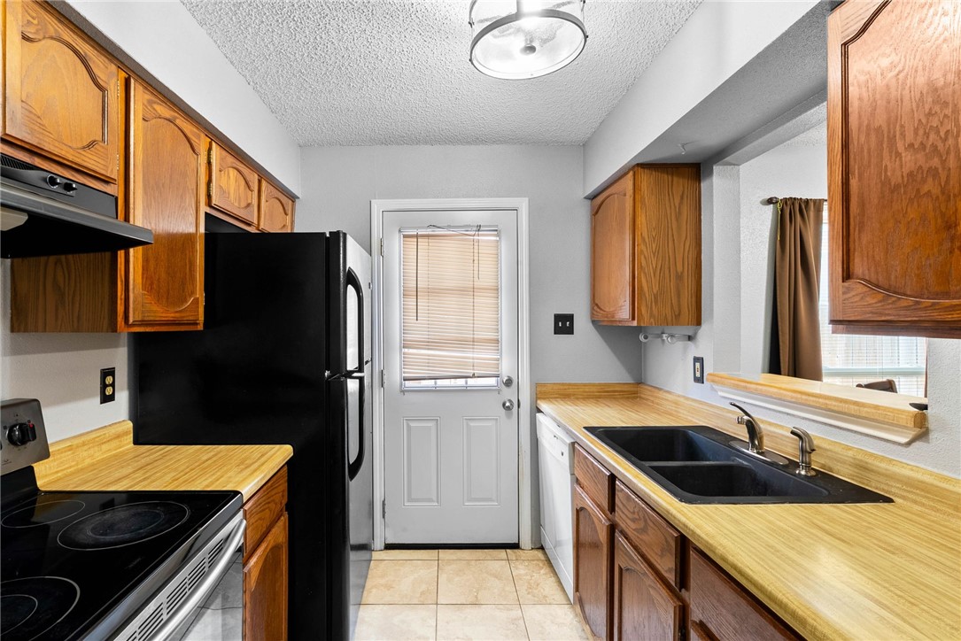 6702 Everhart Road, Unit G105 Corpus Christi, TX 78413 - Photo 7 of 17 a kitchen with granite countertop a refrigerator and a sink