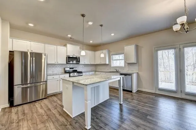 a kitchen with stainless steel appliances granite countertop a refrigerator a sink dishwasher a stove and a refrigerator with wooden floor