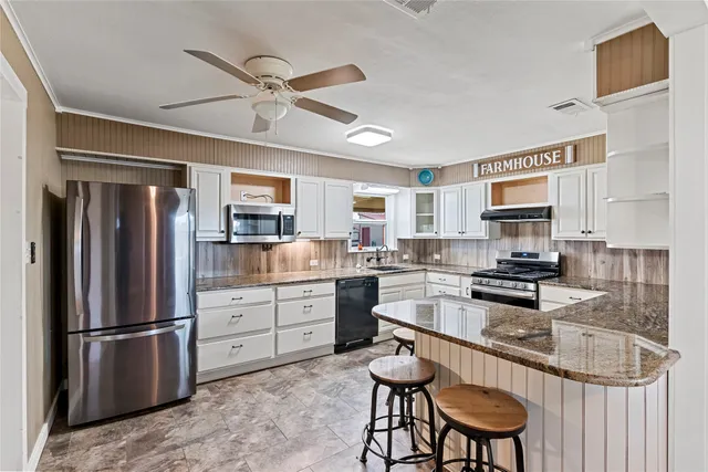 a kitchen with granite countertop stainless steel appliances a stove a sink a refrigerator cabinets and dining table