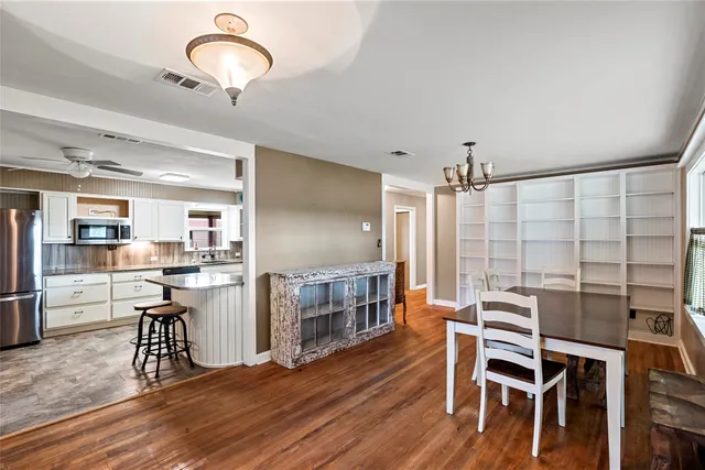 a kitchen with stainless steel appliances kitchen island granite countertop a table chairs cabinets and wooden floor