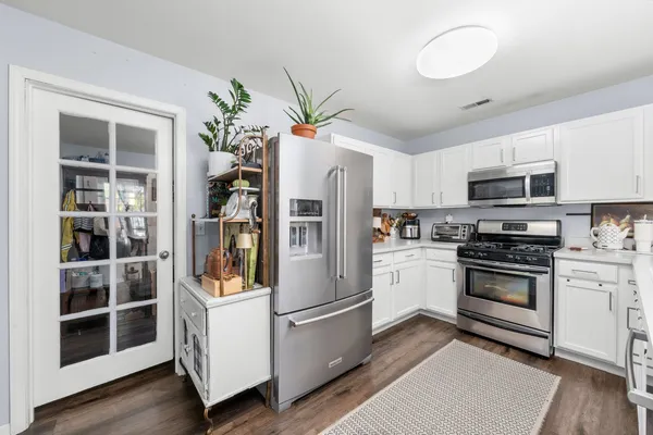 a kitchen with stainless steel appliances a stove a refrigerator cabinets and a dining table