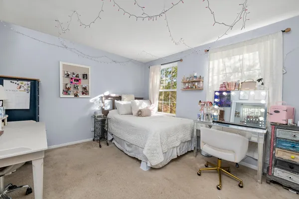 a bedroom with a bed a desk and chair with the wooden floor