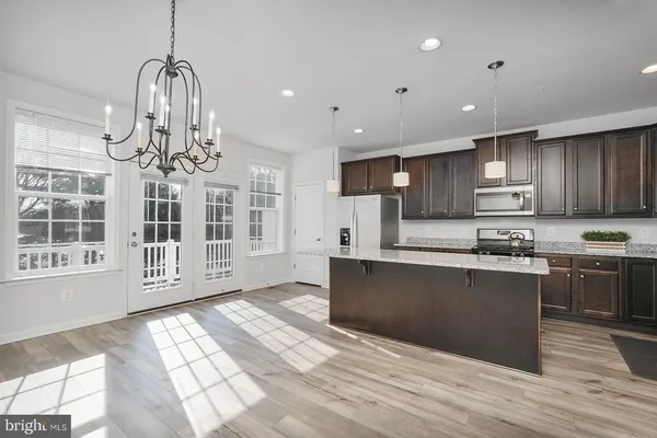 a large kitchen with stainless steel appliances granite countertop a stove a refrigerator a sink dishwasher with a dining table and chairs with wooden floor