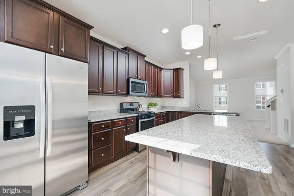 a kitchen with kitchen island granite countertop wooden cabinets and refrigerator