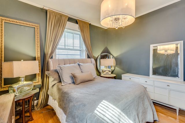 a bedroom with a bed and a large mirror on the dresser