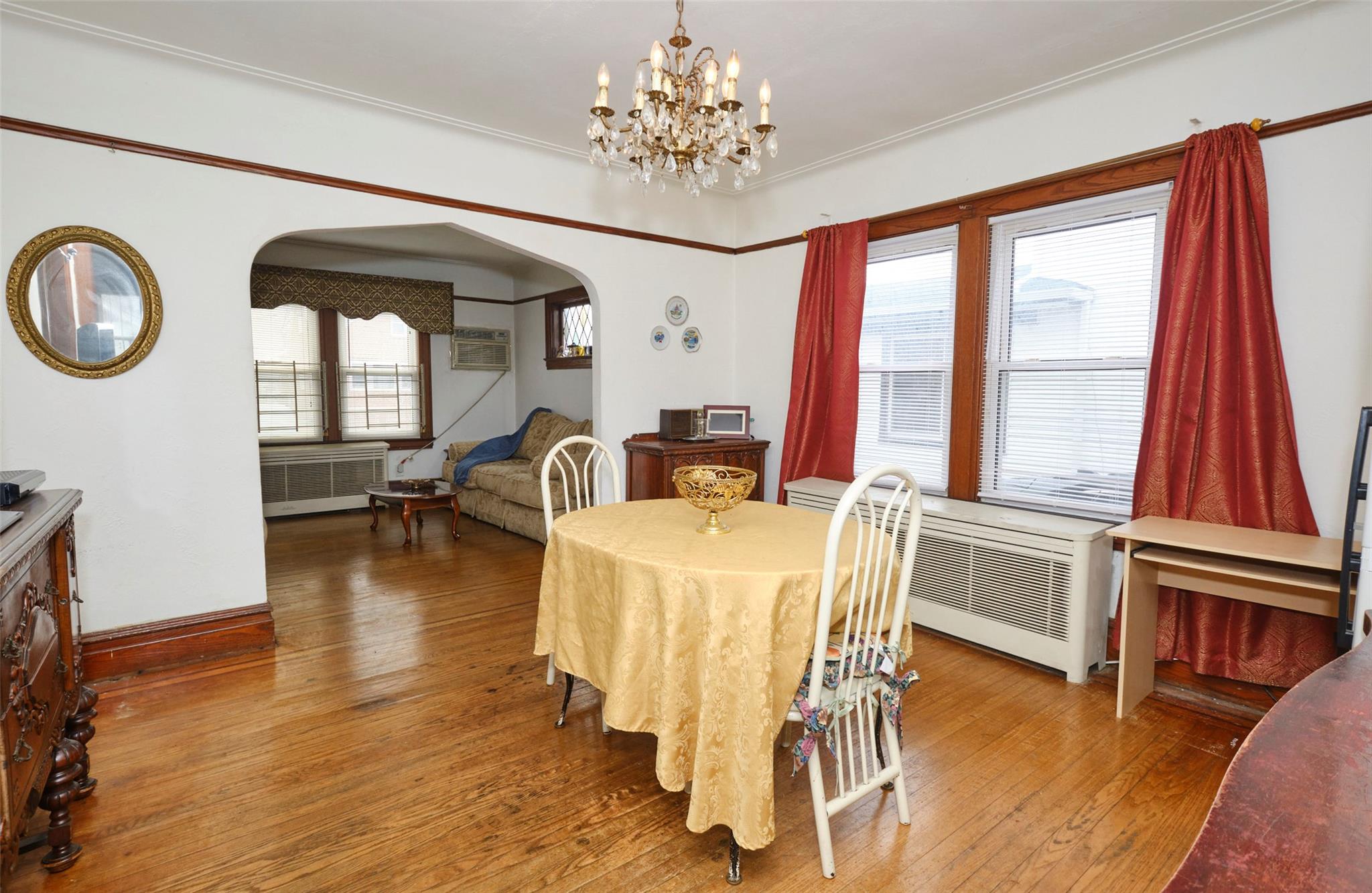 135-47 229th Street Queens, NY 11413 - Photo 11 of 36 Dining area featuring radiator heating unit, arched walkways, hardwood / wood-style flooring, and a chandelier