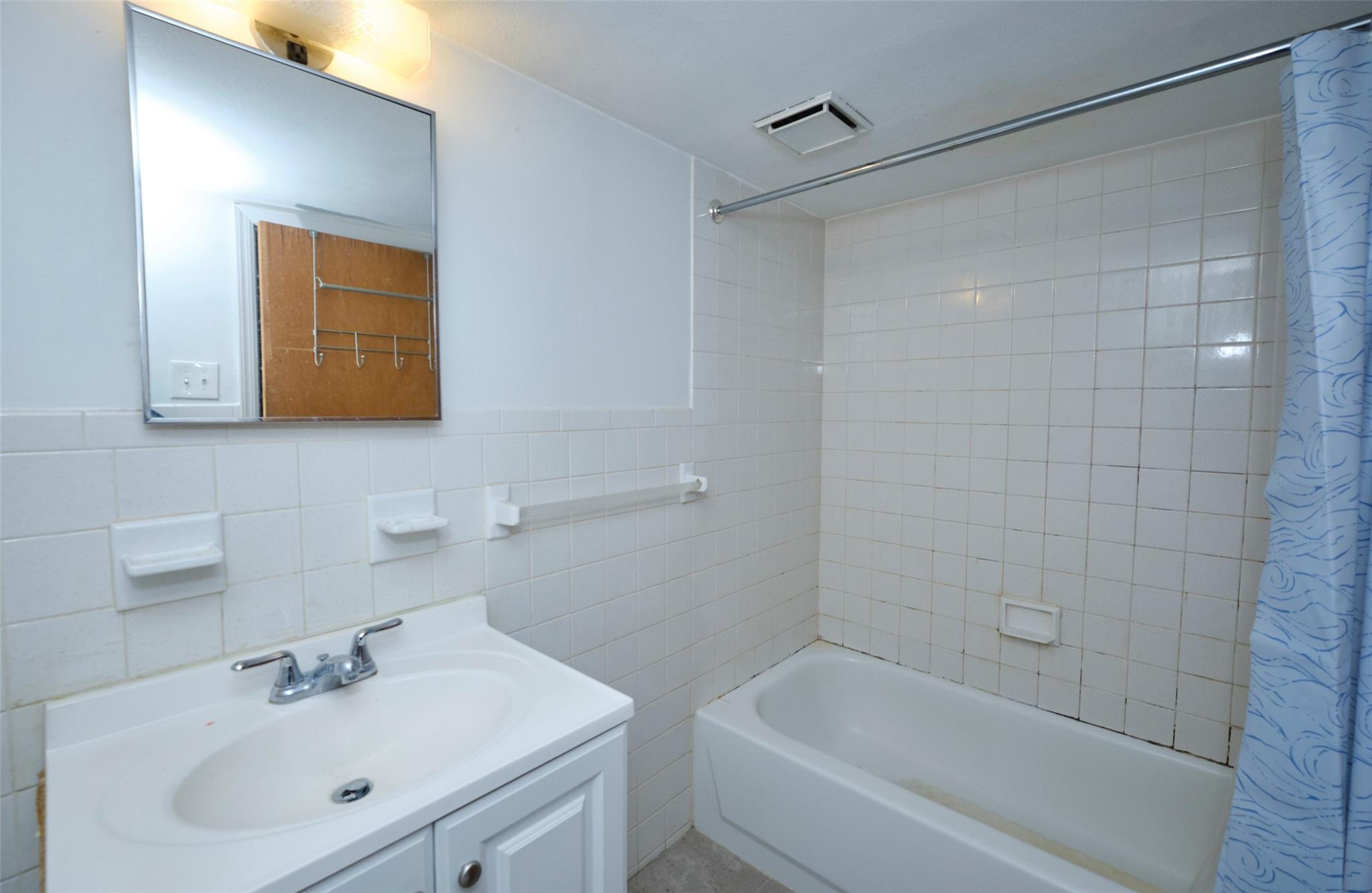 135-47 229th Street Queens, NY 11413 - Photo 25 of 36 Bathroom with a wainscoted wall, vanity, shower / bath combo, visible vents, and tile walls