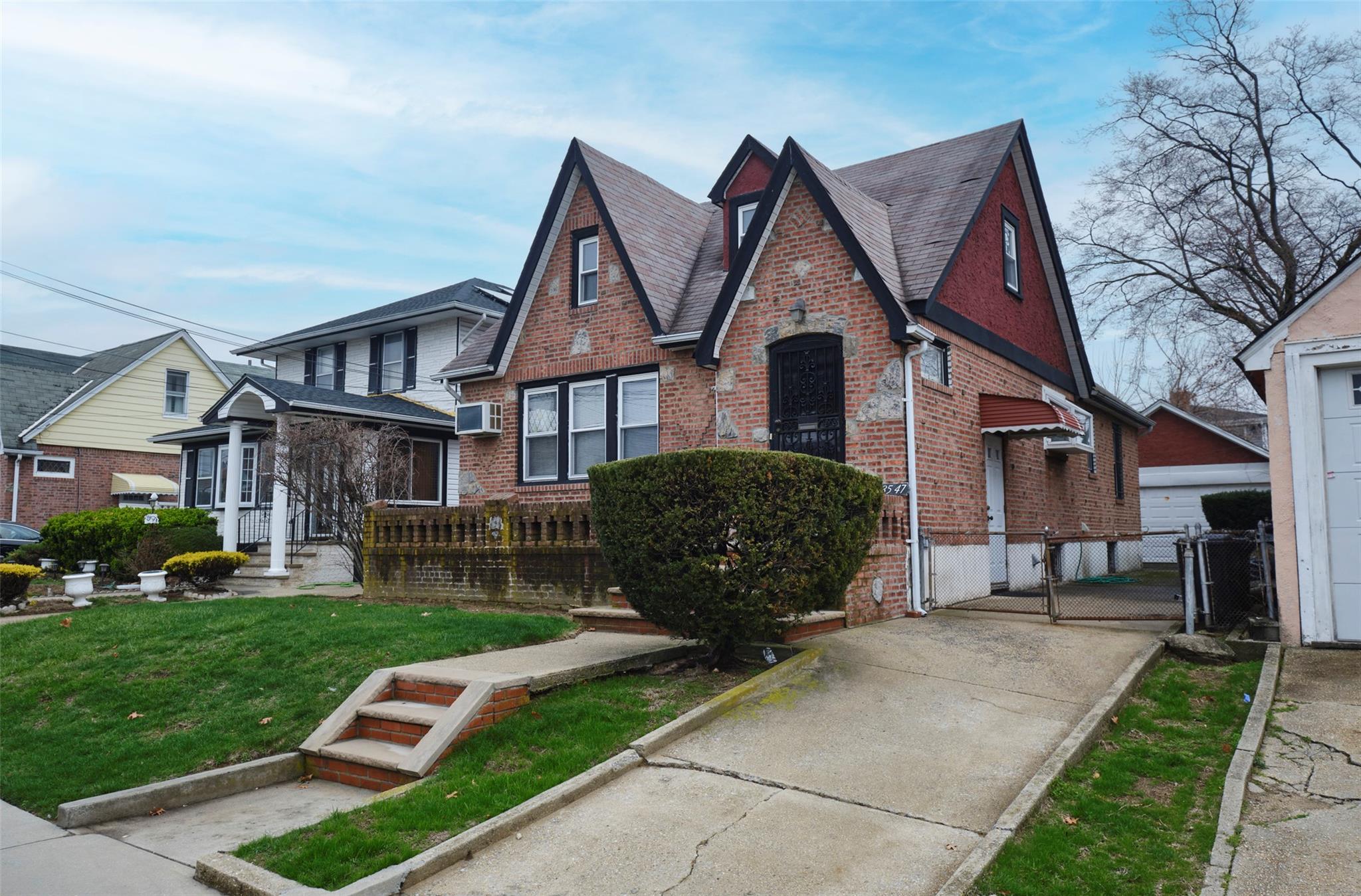 135-47 229th Street Queens, NY 11413 - Photo 35 of 36 English tudor style home with brick siding, a shingled roof, a front lawn